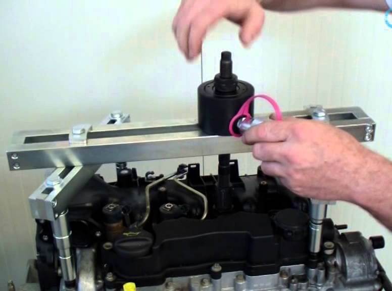 Technician working with a bridge-mounted tool above an engine